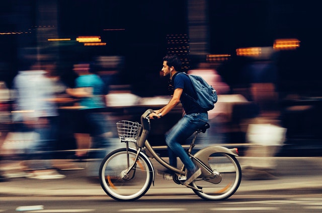 Muž v meste idúci na bicykli