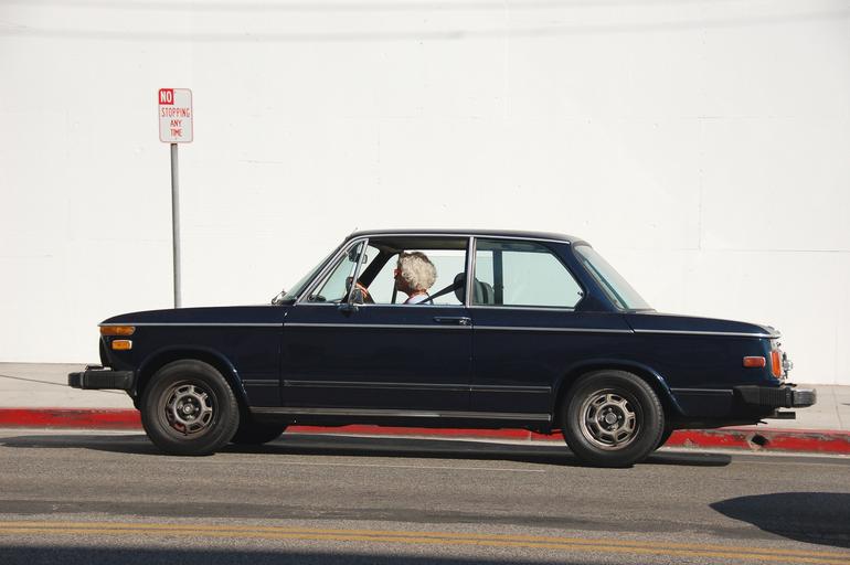 Žena s blond vlasmi šoféruje čierne auto.jpg